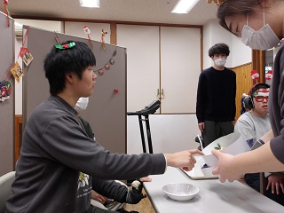 ケーキを差し出す職員と選ぶ児童