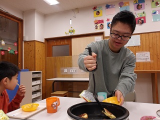 ホットプレートで生地をひっくり返す児童