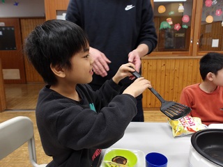 フライ返しを持って笑顔の児童