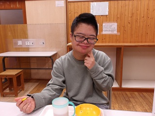 頬に指をあてて笑顔の児童