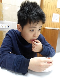 ベビーカステラを千切って食べる児童