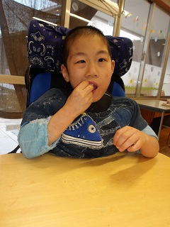 ベビーカステラを片手で食べる児童