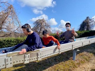 滑り台を滑る児童と職員